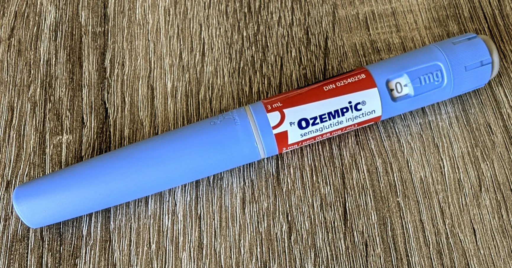 An Ozempic (semaglutide) injection pen, the FDA-approved product that compounded versions copy, lying on a wooden table.