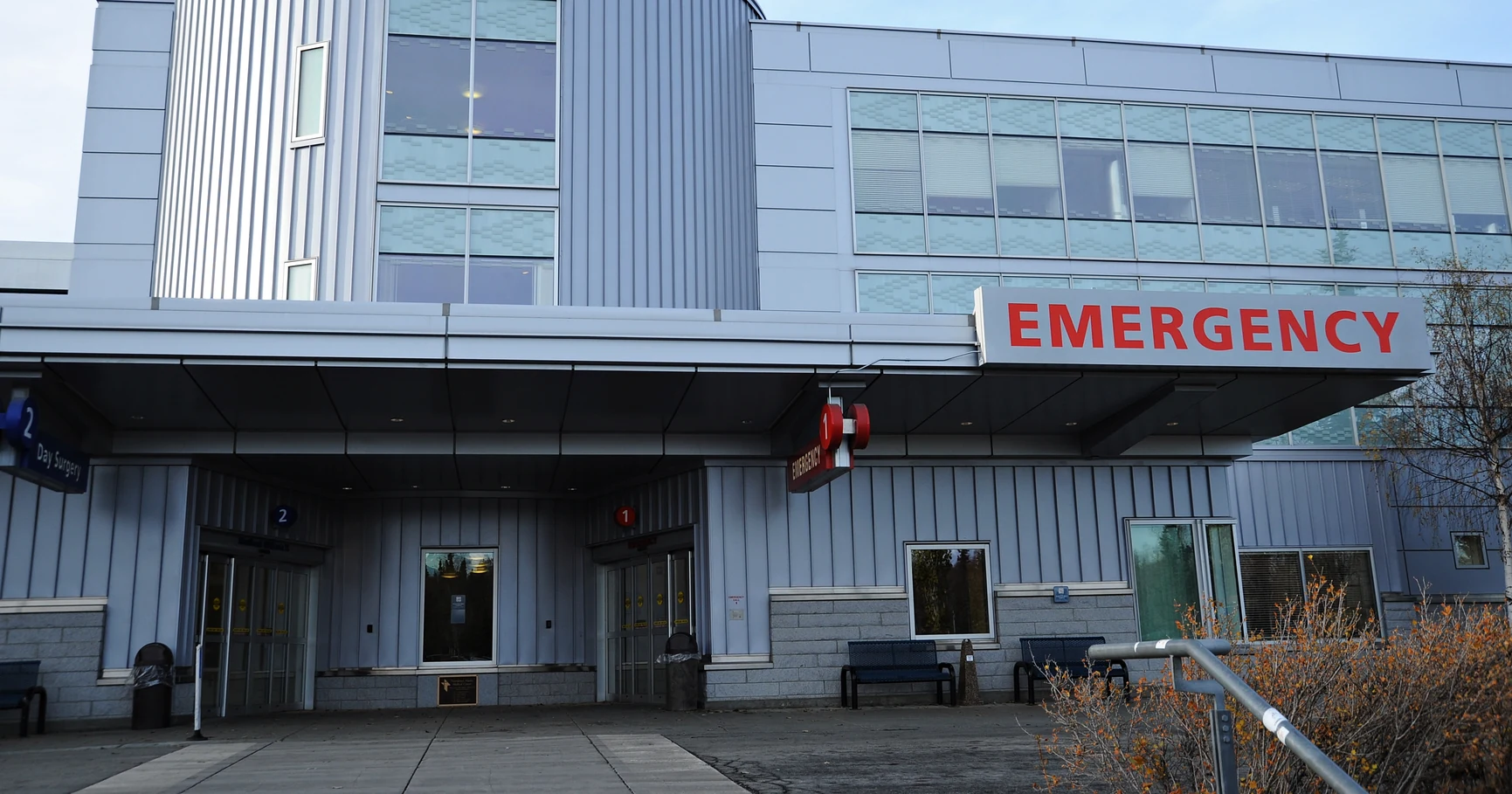 The emergency department entrance of a hospital, with a red EMERGENCY sign above the doors.